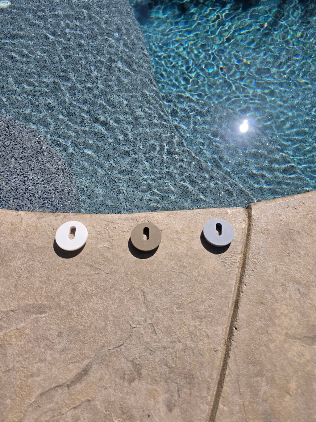 Three MRKSENS replacement deck jet cover plates displayed together beside a swimming pool